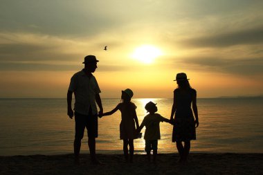 deniz tarafından gün batımında aile silueti