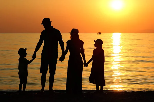 Family silhouette at sunset by the sea... — Stock Photo, Image