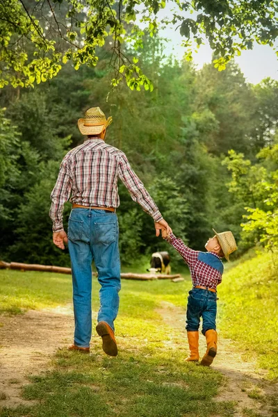 Niño feliz con el padre vaquero en la naturaleza en el campo —  Fotos de Stock