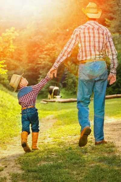 Criança feliz com cowboy pai na natureza no campo — Fotografia de Stock