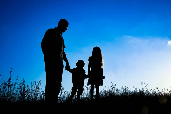 Família feliz ao ar livre na silhueta do parque — Fotografia de Stock