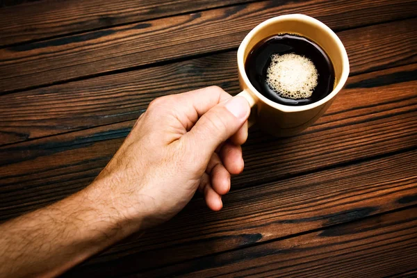 Tangan wanita memegang cangkir kopi dengan latar belakang kayu — Stok Foto
