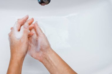 Hygiene concept. Washing hands with soap under the faucet with w clipart