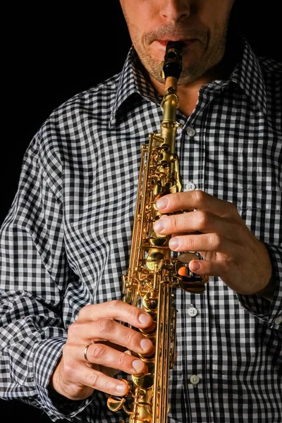 Soprano saxofone em mãos sobre um fundo preto — Fotografia de Stock