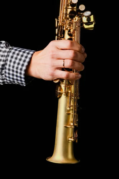 Soprano saxofone em mãos sobre um fundo preto — Fotografia de Stock