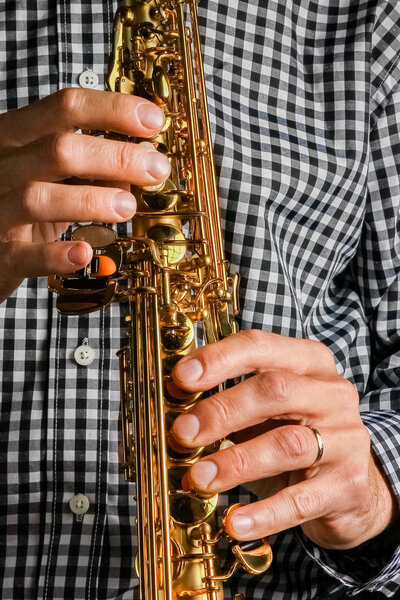 soprano saxophone in hands on a black background