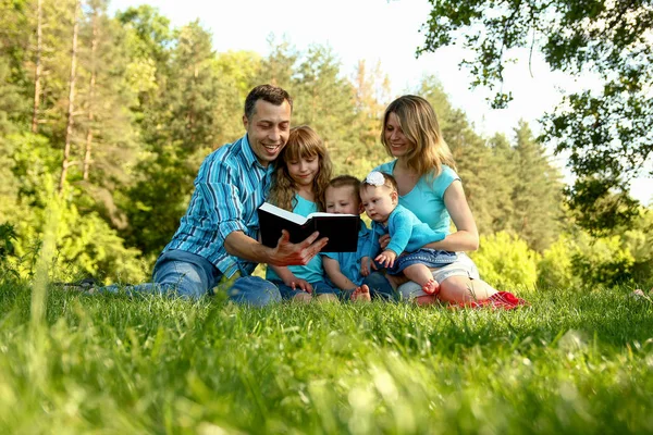 Familia feliz leyendo la Biblia en la naturaleza — Foto de Stock