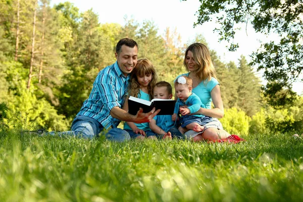 Família feliz lendo a Bíblia na natureza — Fotografia de Stock