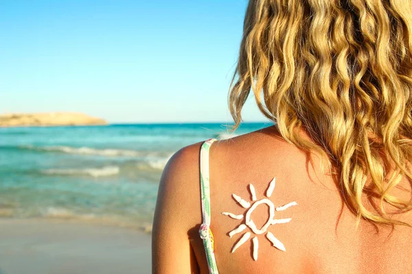 Van zon crème op de vrouwelijke rug op de kust — Stockfoto