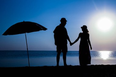 Gün batımında deniz kenarında mutlu bir çift doğada gezici bir siluette