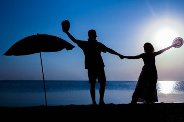 Gün batımında deniz kenarında mutlu bir çift doğada gezici bir siluette