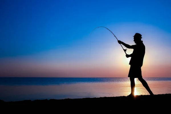 Mutlu Balıkçı Doğa Siluetinde Deniz Kenarında Balık Yakalıyor — Stok fotoğraf