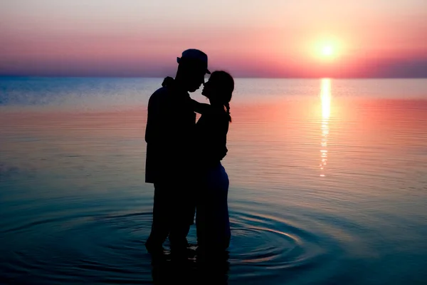 Happy couple by the sea at sunset on travel silhouette in nature