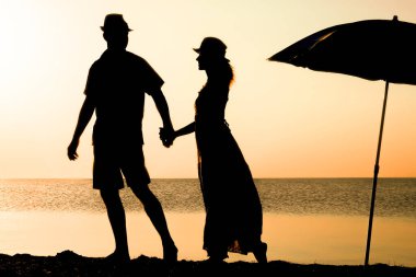 Gün batımında deniz kenarında mutlu bir çift doğada gezici bir siluette