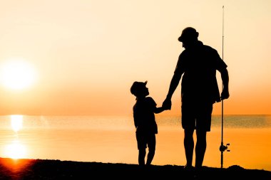 Mutlu baba ve çocuk balıkçılar deniz kenarında balık yakalar.