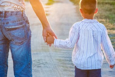 Yolun kenarındaki parkta mutlu bir çocuk ve ebeveynin elleri.
