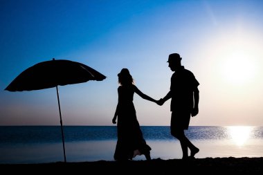 Gün batımında deniz kenarında mutlu bir çift doğada gezici bir siluette