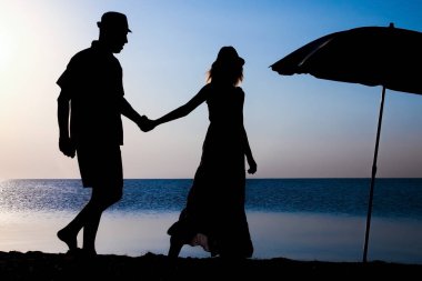 Gün batımında deniz kenarında mutlu bir çift doğada gezici bir siluette