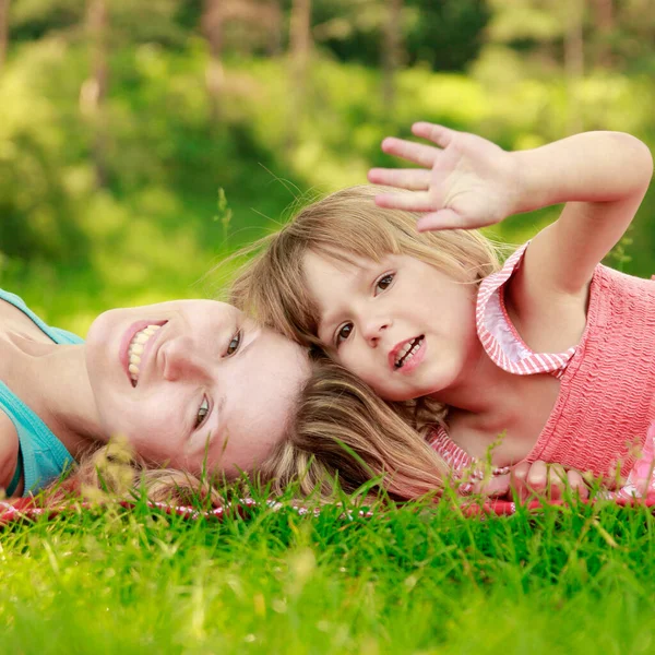 母亲和她快乐的小女儿躺在草地上 — 图库照片