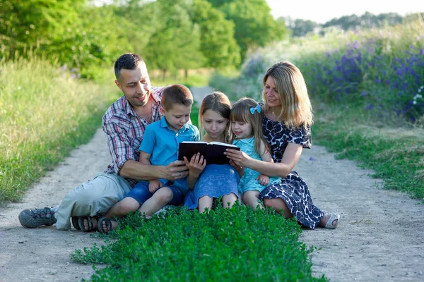 Молодая Счастливая Семья Читает Библию Природе — стоковое фото