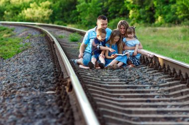  Çocukları demiryolunda İncil okuyan mutlu bir aile.