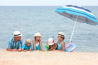 Sahilde kumsalda oynayan mutlu bir aile.