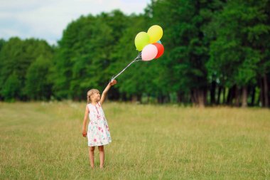 Doğada balonları olan mutlu bir çocuk.