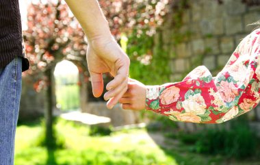 Ebeveyn küçük bir çocuğun elini tutup yürür.