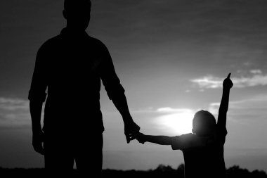 Baba ve oğulun silueti gün batımında oynuyor