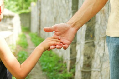 Ebeveyn küçük bir çocuğun elini tutar.