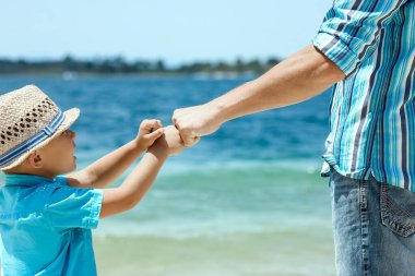 Mutlu baba, Yunan Denizi kıyısında bir çocuğun elini tutuyor.