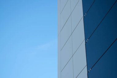 Mavi gökyüzüne karşı modern bir siyah beyaz dış metal panel duvar. Alüminyum kompozit paneller.