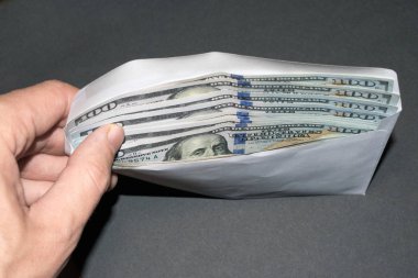 Gri bir arka planda içinde para olan bir adamın el ele tutuşması.
