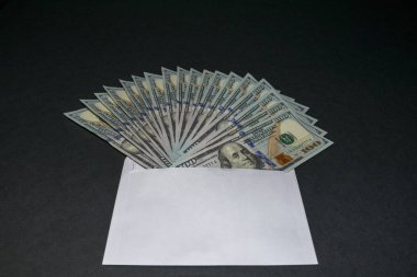 Yüz dolarlık banknotlar beyaz boş zarftan çıkıntı. Beyaz ön planda yer kopyalama.