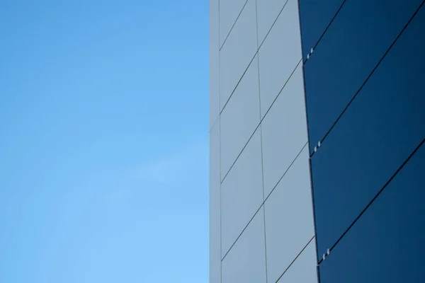 Mavi gökyüzüne karşı modern bir siyah beyaz dış metal panel duvar. Alüminyum kompozit paneller.