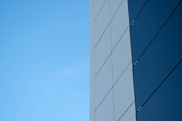 A modern black and white exterior metal panel wall against a blue sky. Aluminum composite panels.