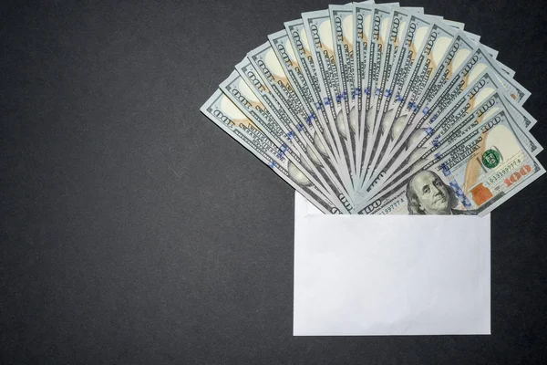 Money in the envelope on a black background with copy space on the left. Envelope full of money.