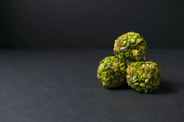 Fitness snack. Middle East pistachio candy. Scattered pistachio nuts. Copy space. Dark background.