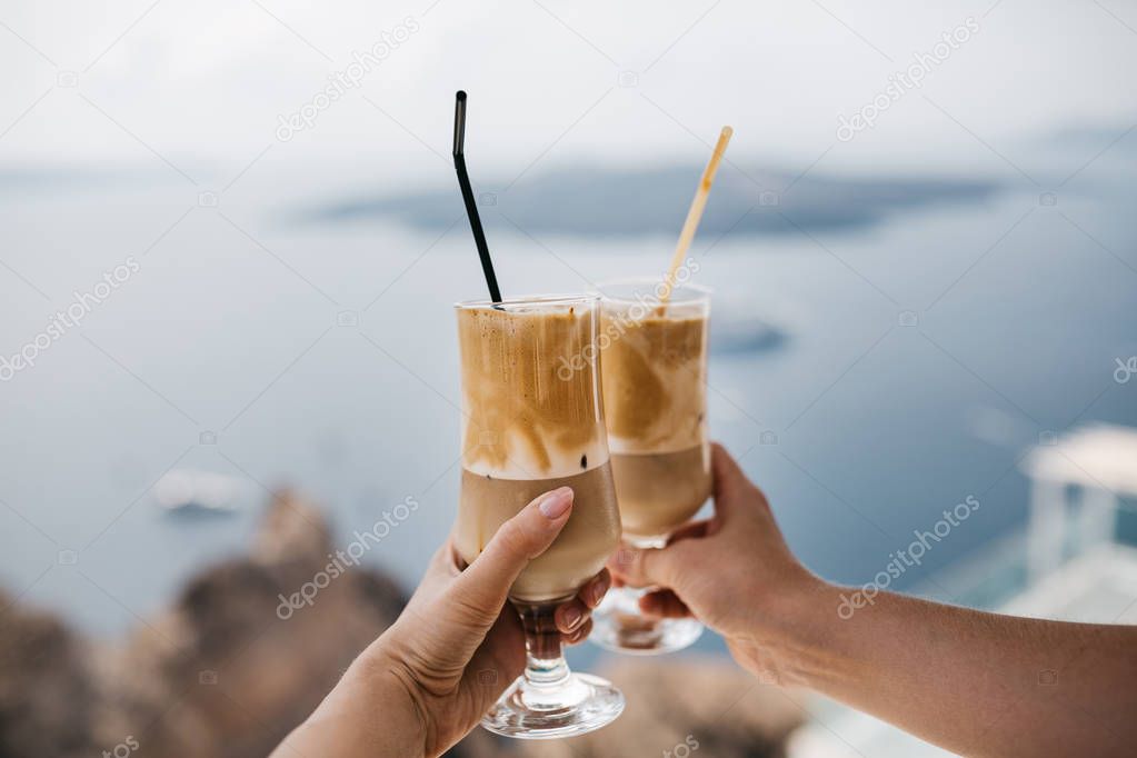 cropped image of couple having cold coffee in majestic Santorini, South Aegean, Thira, Santorini, Greece 