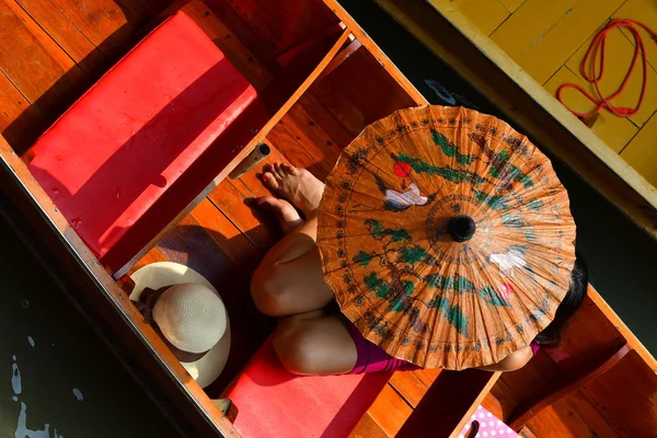 overhead view of Woman with umbrella in boat, Thailand floating market