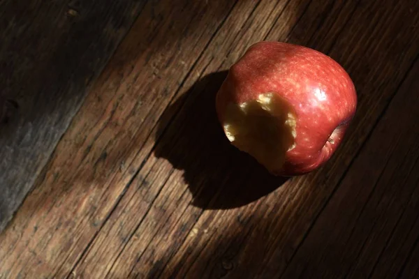 Roter Apfel Mit Einem Loch Das Auf Einer Braunen Holzoberfläche — Stockfoto
