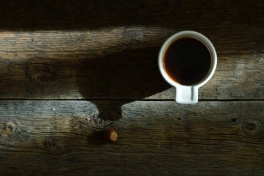 Fincan kahve ve ahşap masa arka plan üzerinde güneş ışığı 