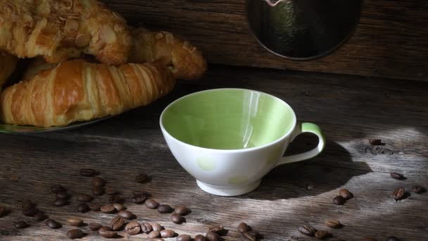古い木製のテーブルの背景にクロワッサンとコーヒーのカップ のイメージ コーヒー気分 — ストック動画