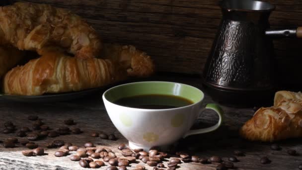 古い木製のテーブルの背景にクロワッサンとコーヒーのカップ のイメージ コーヒー気分 — ストック動画