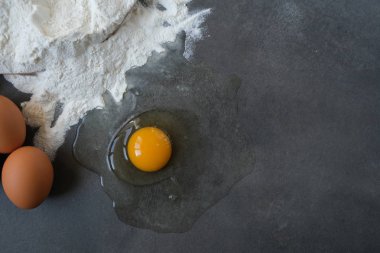 Koyu arkaplanda yumurta ve buğday unu (pişirme, ekmek ve diğer hamur işleri için malzemeler))