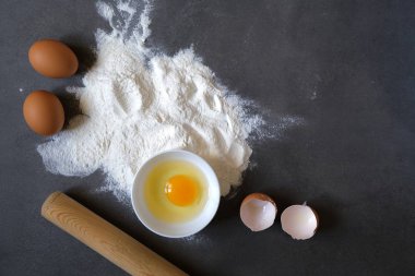 Koyu arkaplanda yumurta ve buğday unu (pişirme, ekmek ve diğer hamur işleri için malzemeler))