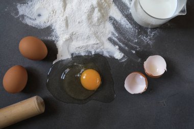 Koyu arkaplanda yumurta ve buğday unu (pişirme, ekmek ve diğer hamur işleri için malzemeler))