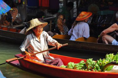 Damnoen Saduak Yüzen Pazarı, Tayland - 7 Ekim 2008: Yaşlı bir kadın teknesinden turistlere yeşil muz satıyor. Sokak yemeği..