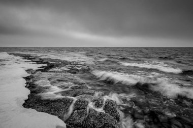 Siyah ve beyaz fotoğraf stoney kıyı ile kar için acele dalgaların