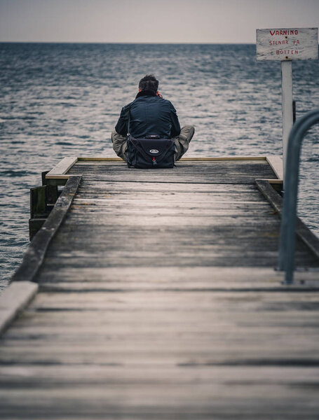 man sitting on a wooden jetty